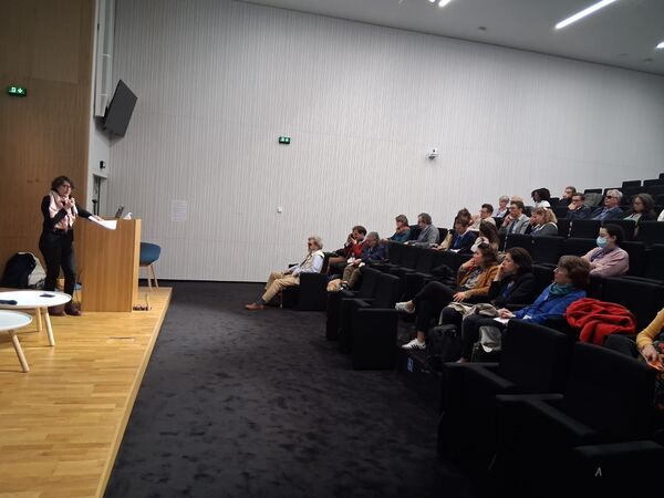 L'amphithéâtre du Centre de Colloques du Campus Condorcet, sur la scène Stéphanie Biegler, devant elle des membres de structures intéressées par le Conseil en Orientation et Stratégie, assis.
